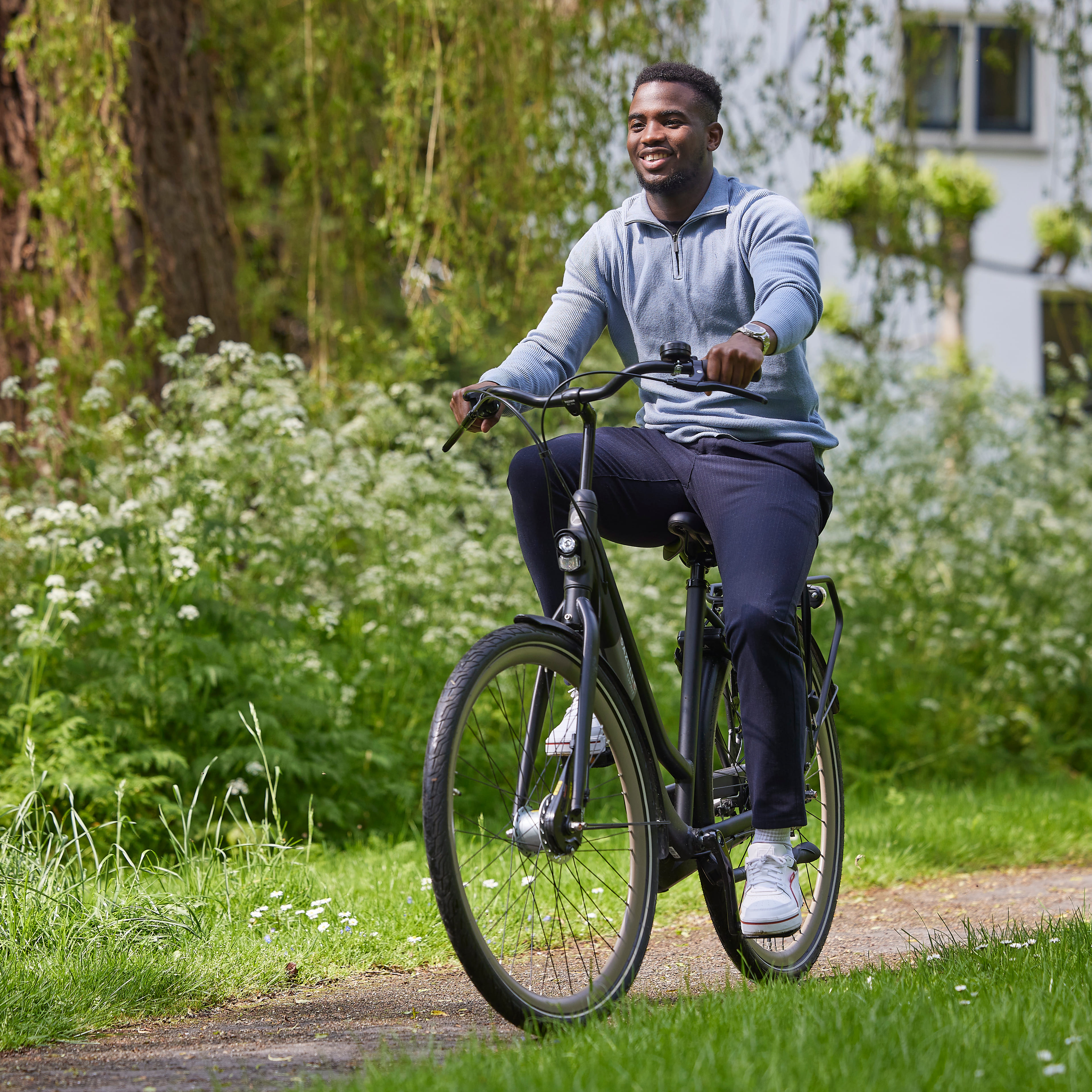 Een man op de fiets. Hij fietst door een park.