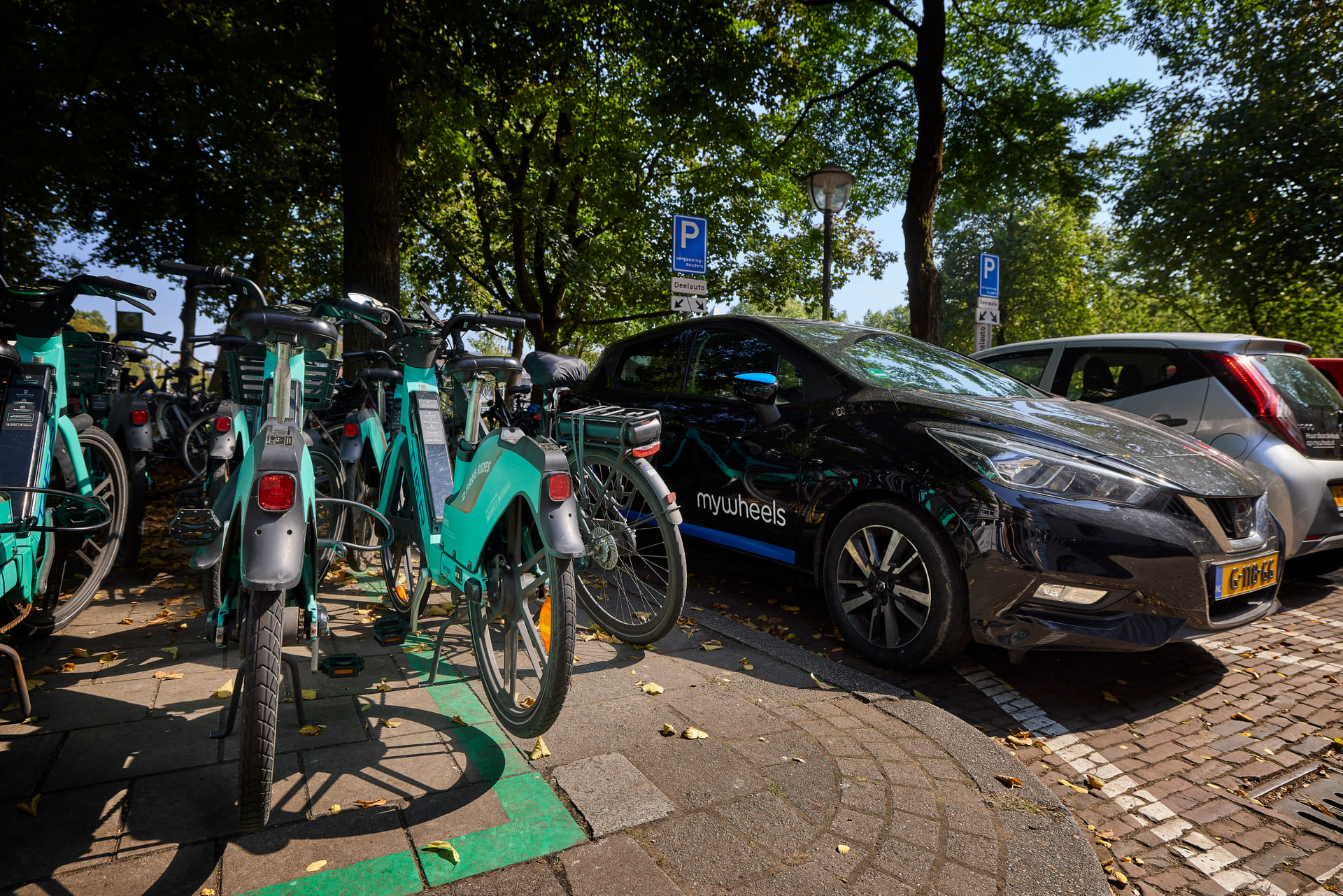 Een deelfiets en een deelauto naast elkaar geparkeerd