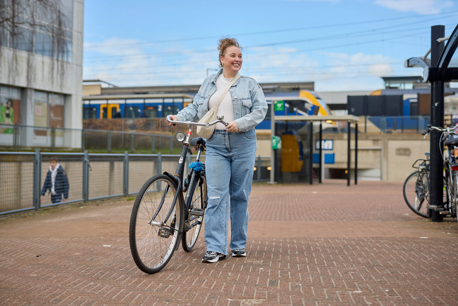 Je ziet een dame naast haar eigen fiets lopen op station Amersfoort Schothorst